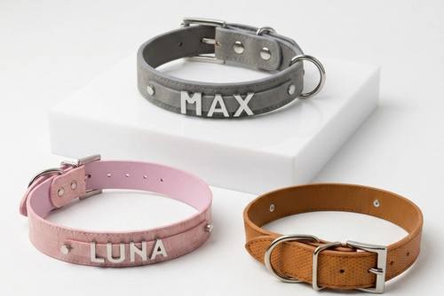 Three personalized dog collars displayed on a clean white background: a gray collar labeled 'MAX', a pink collar labeled 'LUNA', and a tan collar with a silver buckle.