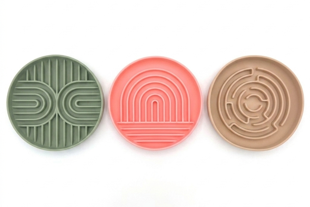 Three round silicone coasters in sage green, coral pink, and tan, each featuring a unique embossed geometric pattern, arranged horizontally on a white background.