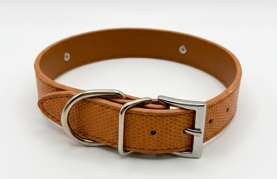 A tan textured leather dog collar with a silver-tone metal buckle and D-ring, displayed on a clean white background.