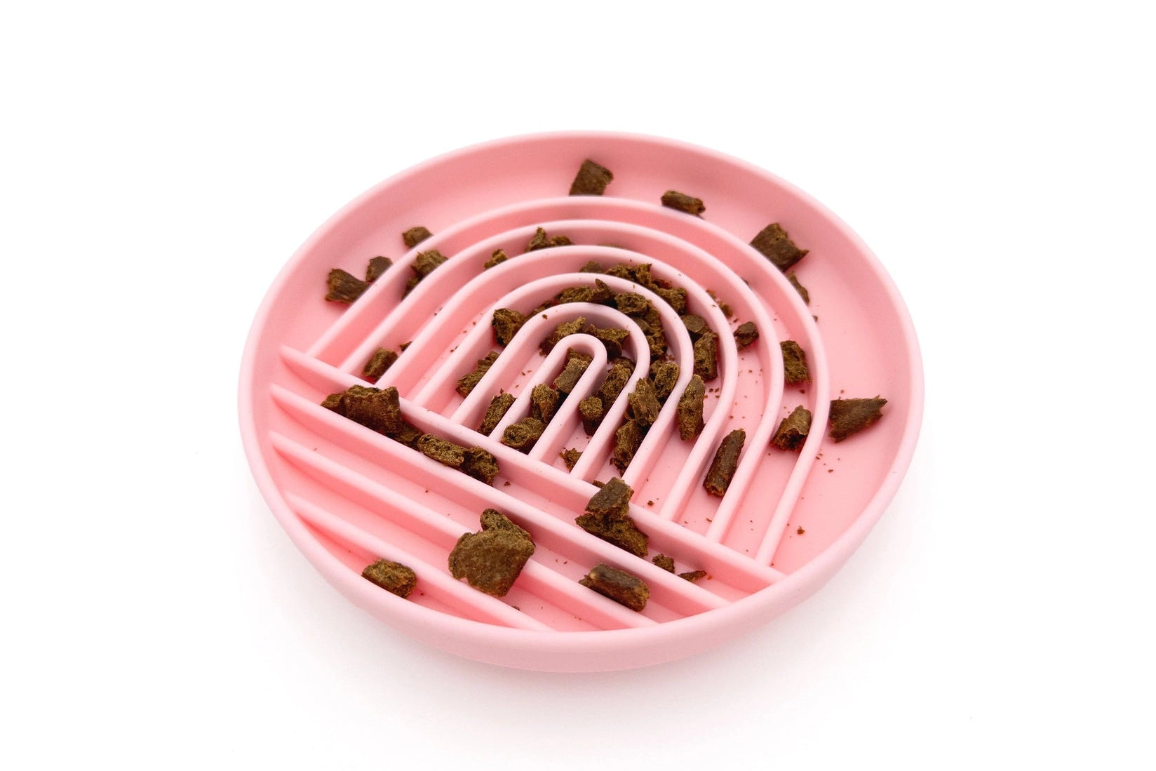 A pink silicone pet puzzle feeder with a spiral maze design, shown on a clean white background with some kibble pieces scattered inside.