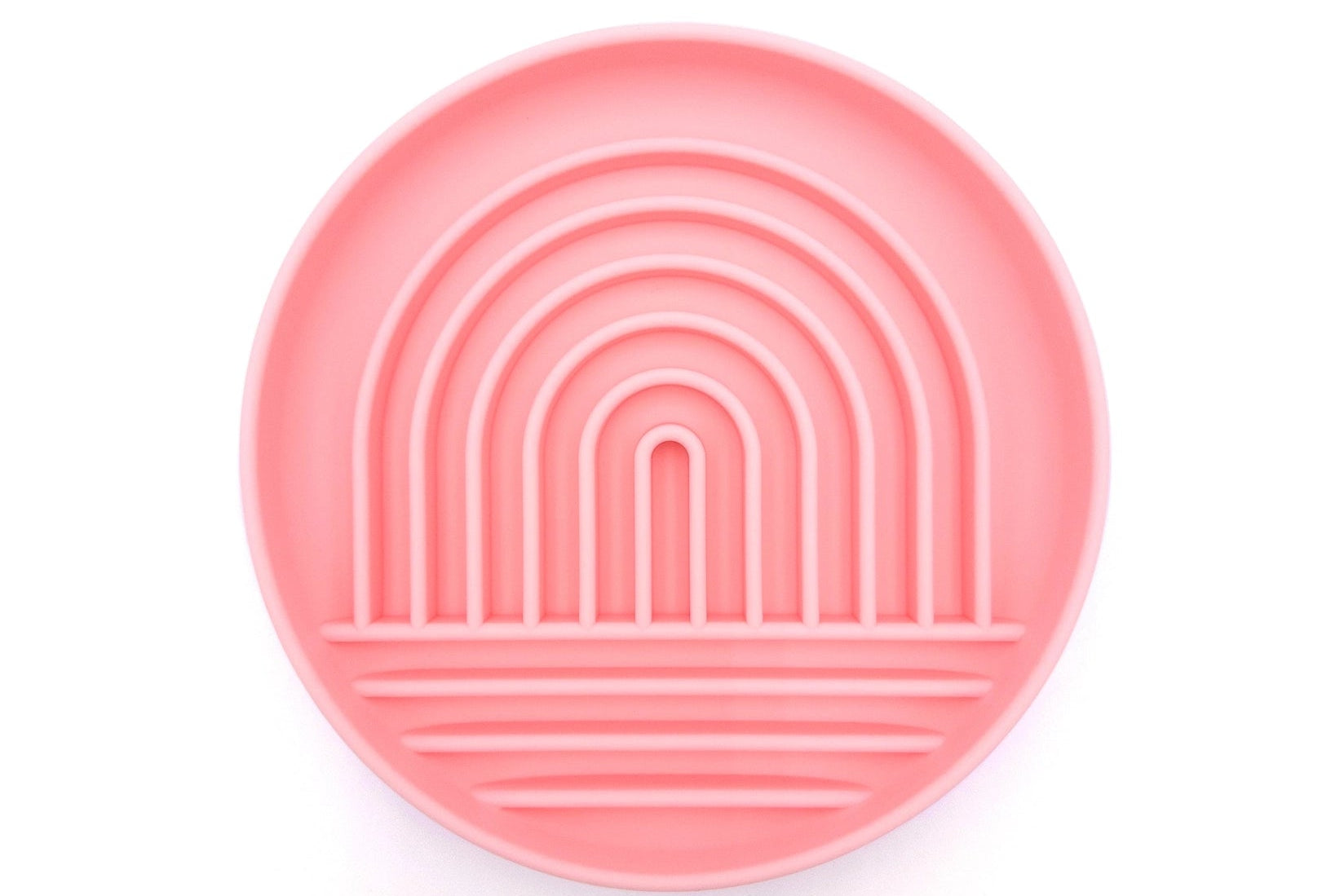 A round pink silicone plate with concentric rainbow arches and horizontal ridges, shown from a top-down view on a white background.